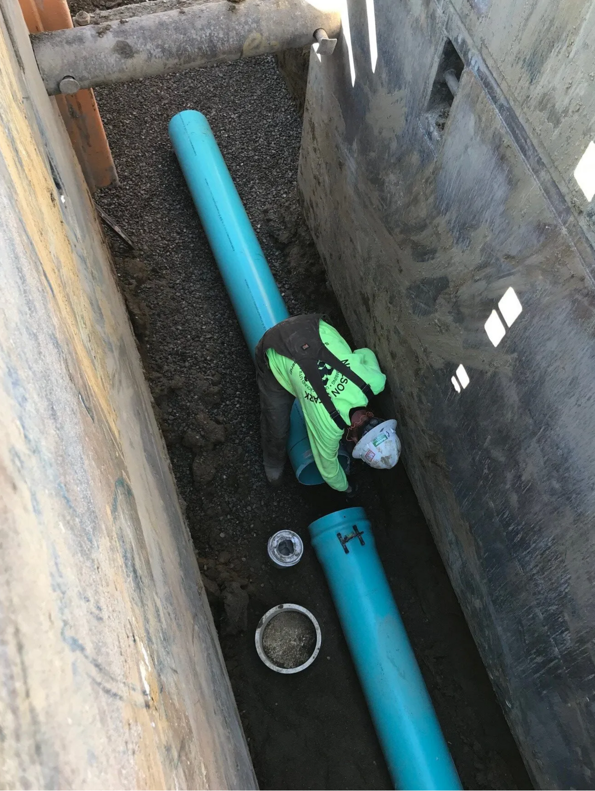 Worker connecting pipe in a trench