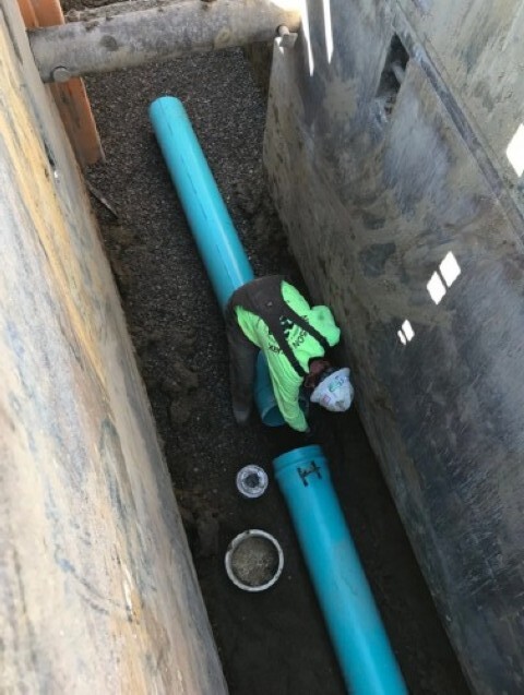 Worker connecting pipe in a trench